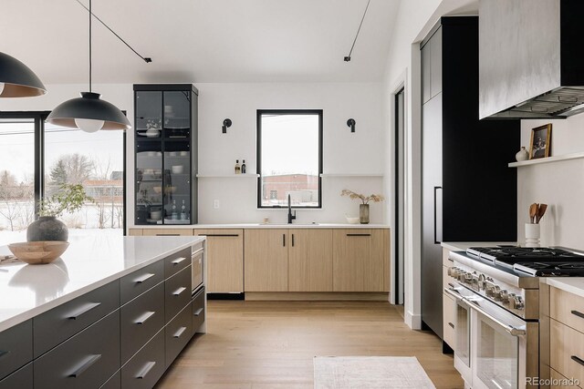 kitchen featuring pendant lighting, sink, range with two ovens, and light brown cabinets