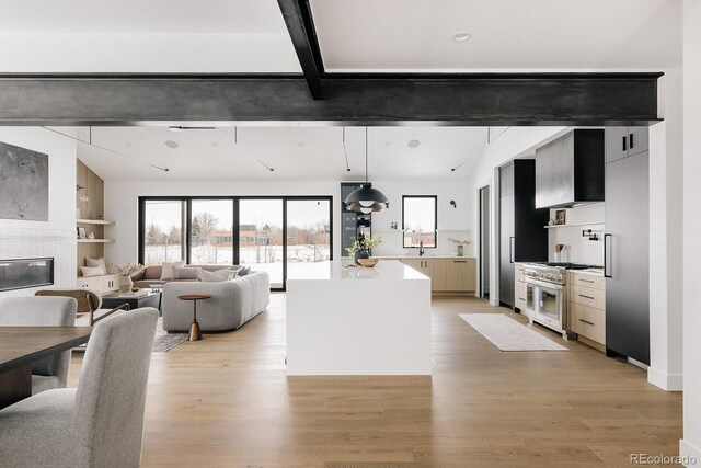 kitchen with a tile fireplace, light hardwood / wood-style floors, decorative light fixtures, beamed ceiling, and range with two ovens