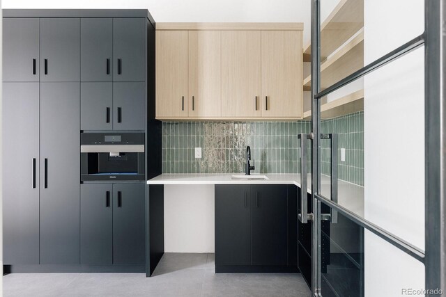 kitchen featuring gray cabinets, tasteful backsplash, sink, oven, and light brown cabinets