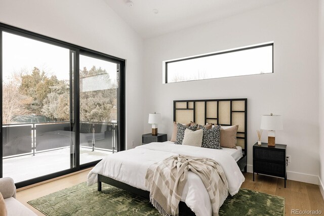 bedroom with access to exterior, vaulted ceiling, and hardwood / wood-style floors