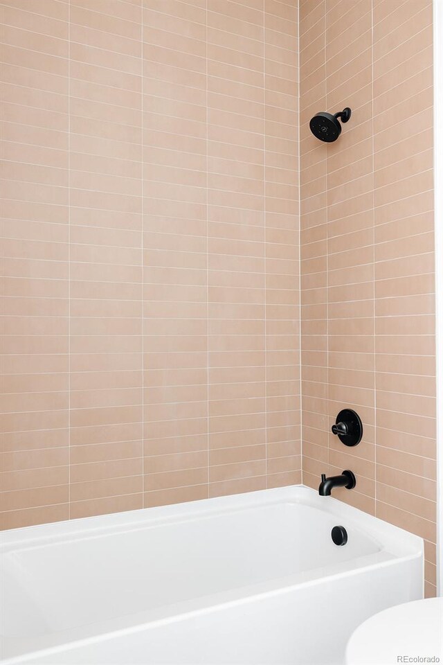 bathroom with tiled shower / bath and toilet