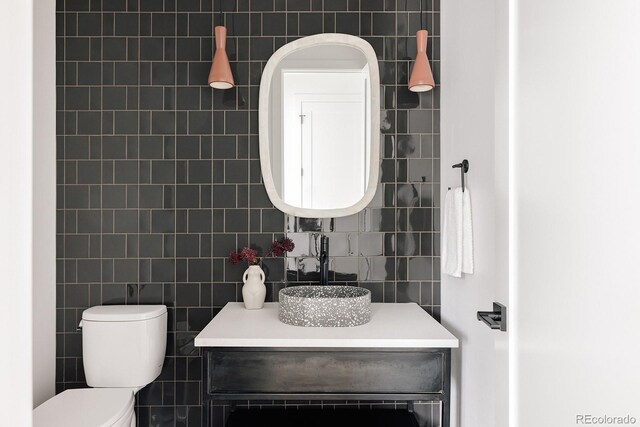 bathroom featuring vanity, tile walls, and toilet