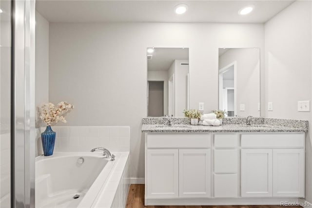 bathroom featuring tiled bath, vanity, and hardwood / wood-style flooring