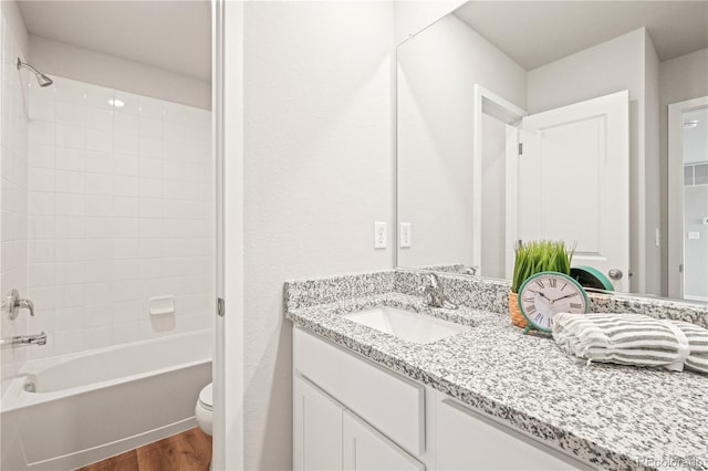 full bathroom featuring hardwood / wood-style floors, vanity, shower / bath combination, and toilet