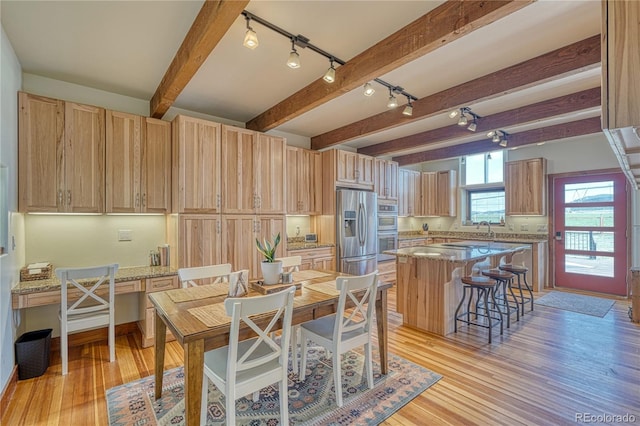 dining room featuring beamed ceiling, light hardwood / wood-style floors, and sink