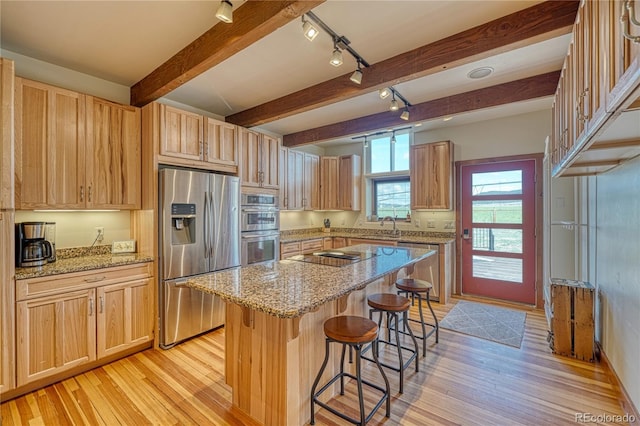 kitchen with beamed ceiling, light wood-type flooring, a kitchen island, and appliances with stainless steel finishes