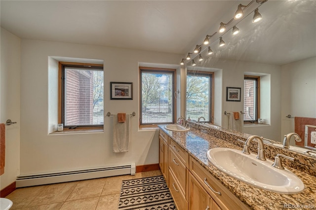 bathroom featuring a healthy amount of sunlight, vanity with extensive cabinet space, a baseboard radiator, and dual sinks