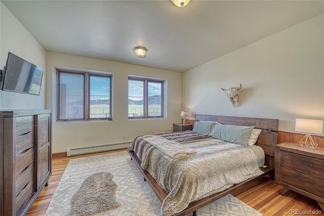 bedroom featuring a baseboard heating unit and light wood-type flooring