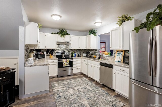 kitchen featuring white cabinets, light stone counters, stainless steel appliances, and dark hardwood / wood-style floors