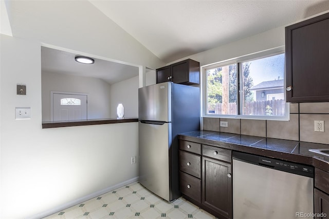 3570 Center Ave, Denver, CO 80219 - kitchen featuring appliances with stainless steel finishes, dark brown cabinetry, vaulted ceiling, light flooring, and tile countertops