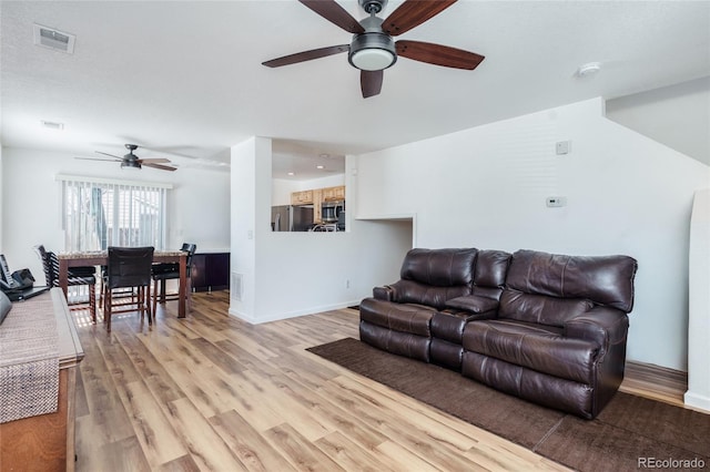 living area with a ceiling fan, light wood-type flooring, visible vents, and baseboards