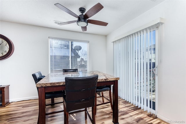 dining room featuring light wood-type flooring, baseboards, and a ceiling fan