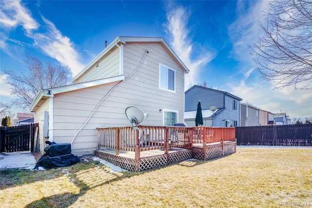 back of property with a fenced backyard, a deck, and a lawn