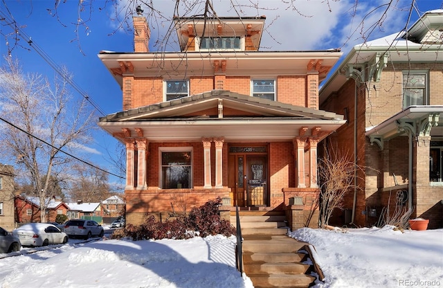 american foursquare style home featuring a porch and brick siding