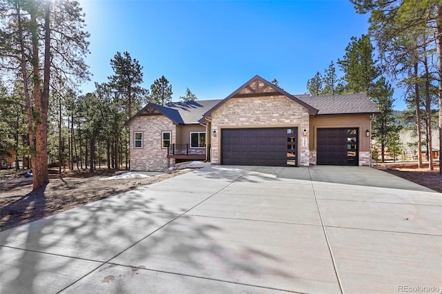 view of front of home with an attached garage, stone siding, driveway, and roof with shingles