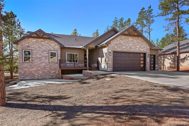 view of front of home featuring stone siding, an attached garage, a shingled roof, and driveway
