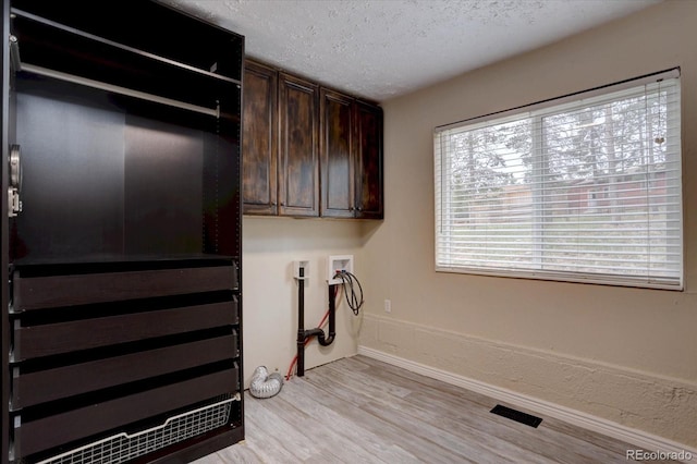 9288 Krashin Dr, Conifer, CO 80433 - laundry room featuring cabinet space, light wood-type flooring, baseboards, washer hookup, and a textured ceiling