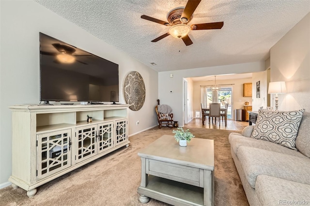 living room with light carpet, a textured ceiling, and ceiling fan with notable chandelier