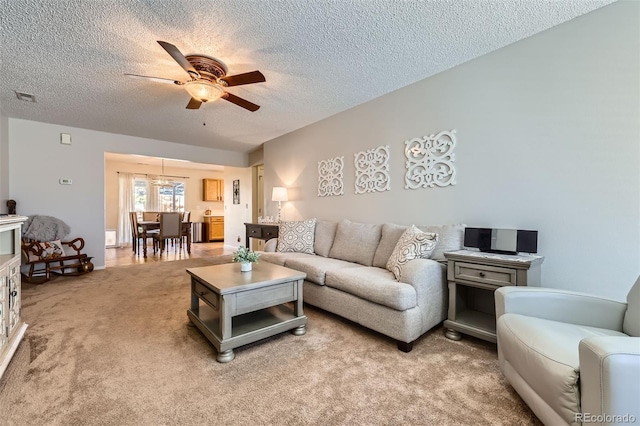 living room with ceiling fan, light colored carpet, and a textured ceiling