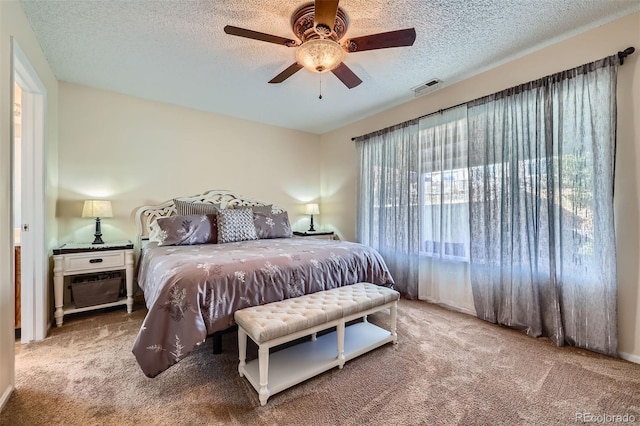 carpeted bedroom with ceiling fan and a textured ceiling