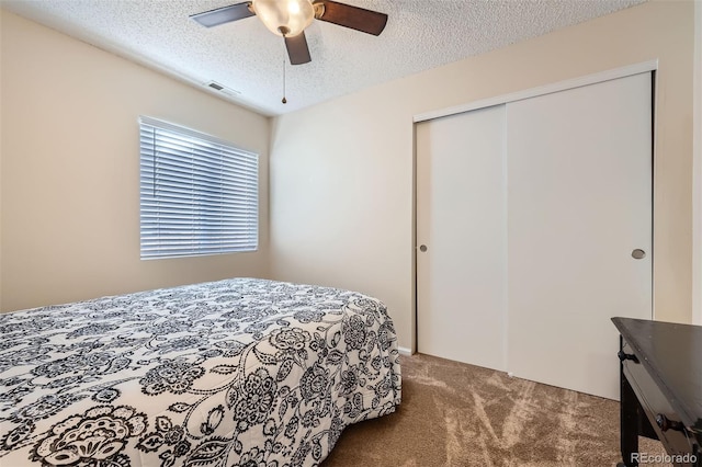 carpeted bedroom featuring ceiling fan, a closet, and a textured ceiling