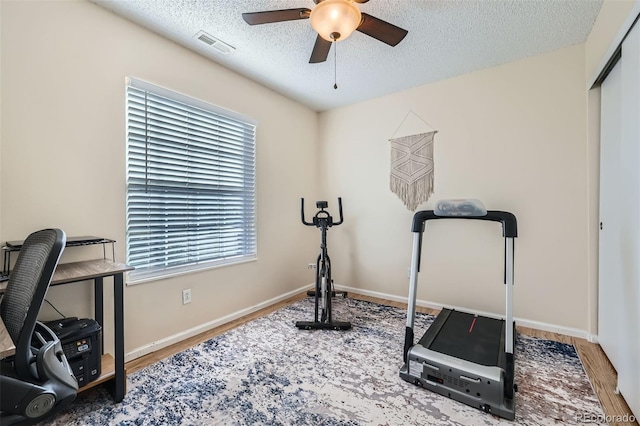 workout area with a wealth of natural light, ceiling fan, a textured ceiling, and hardwood / wood-style flooring