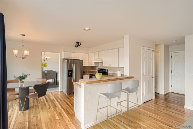 16645 W 2nd Ave, Golden, CO 80401 - kitchen featuring appliances with stainless steel finishes, under cabinet range hood, light wood-type flooring, a peninsula, and a chandelier
