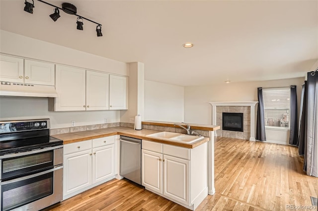 16645 W 2nd Ave, Golden, CO 80401 - kitchen with appliances with stainless steel finishes, under cabinet range hood, a peninsula, white cabinets, and light wood finished floors