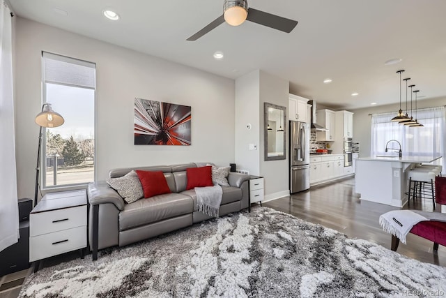 living room featuring dark wood-style floors, baseboards, a ceiling fan, and recessed lighting