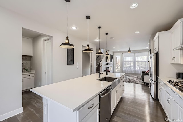 kitchen with stainless steel appliances, dark wood-type flooring, a sink, light countertops, and a center island with sink