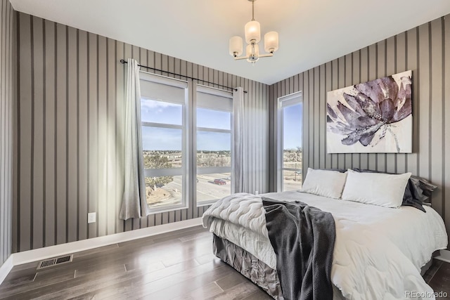 bedroom with dark hardwood / wood-style flooring and an inviting chandelier