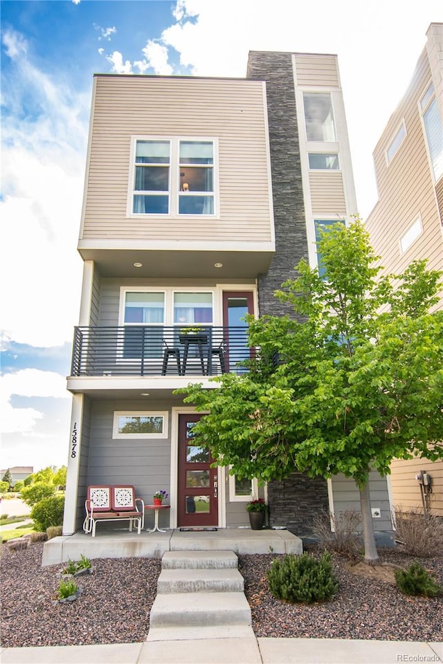 15878 E Broncos Pl, Englewood, CO 80112 - contemporary home with a balcony, covered porch, and stone siding