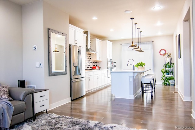 15878 E Broncos Pl, Englewood, CO 80112 - kitchen featuring stainless steel fridge with ice dispenser, white double oven, a kitchen bar, dark wood-type flooring, and a kitchen island with sink
