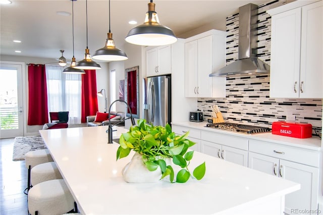 15878 E Broncos Pl, Englewood, CO 80112 - kitchen with wall chimney range hood, appliances with stainless steel finishes, an island with sink, light countertops, and backsplash