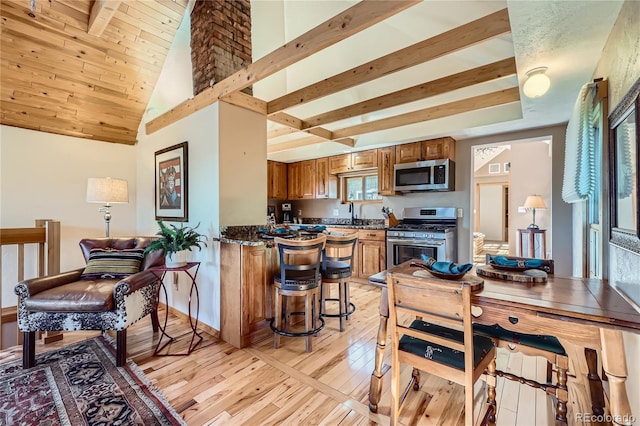 903 High Rd, Manitou Springs, CO 80829 - kitchen with stainless steel appliances, brown cabinetry, light wood finished floors, a peninsula, and a breakfast bar area