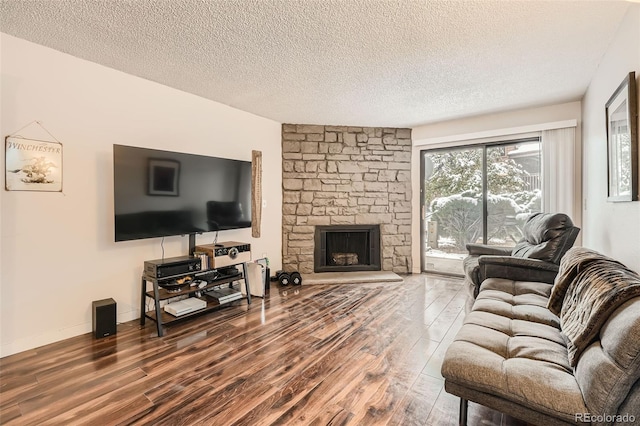 living room featuring hardwood / wood-style floors, a stone fireplace, and a textured ceiling