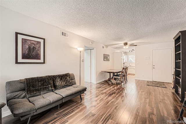 living room with wood-type flooring, a textured ceiling, and ceiling fan