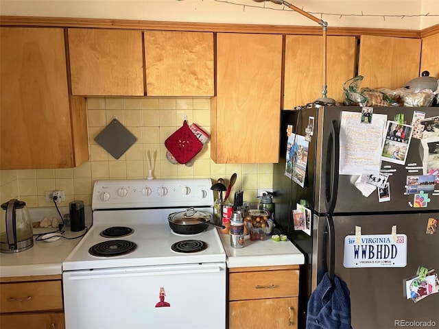 kitchen with white electric stove, stainless steel fridge, and decorative backsplash