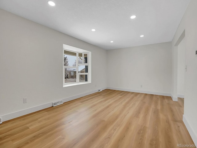 unfurnished room with light wood-type flooring, visible vents, baseboards, and recessed lighting