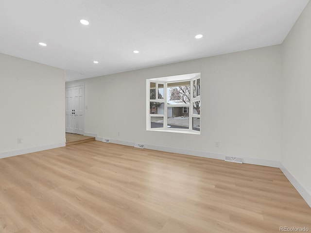 empty room featuring baseboards, light wood-style floors, visible vents, and recessed lighting