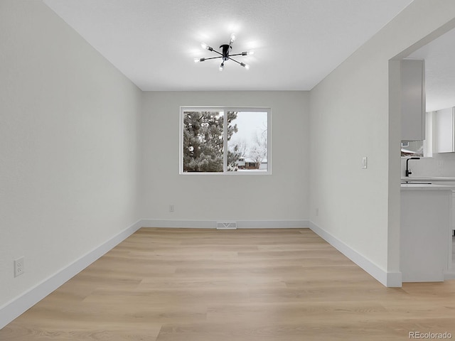 8694 E Eastman Ave, Denver, CO 80231 - unfurnished dining area with a chandelier, baseboards, and light wood-style flooring