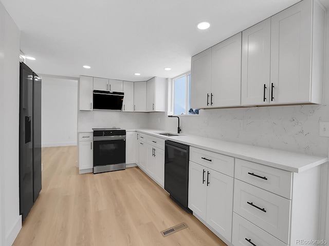 8694 E Eastman Ave, Denver, CO 80231 - kitchen with range with electric stovetop, black dishwasher, a sink, light wood-style floors, and backsplash