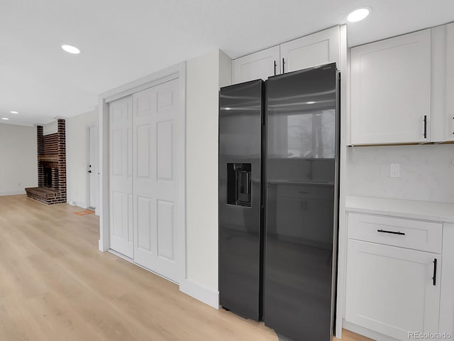 8694 E Eastman Ave, Denver, CO 80231 - kitchen with black fridge with ice dispenser, light wood-style floors, white cabinetry, light countertops, and recessed lighting