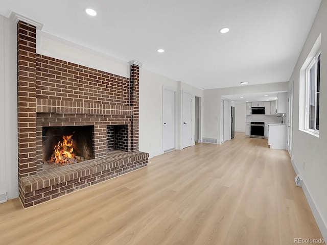 8694 E Eastman Ave, Denver, CO 80231 - unfurnished living room with a brick fireplace, light wood-style flooring, baseboards, and recessed lighting