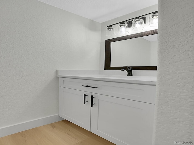 8694 E Eastman Ave, Denver, CO 80231 - bathroom with a textured wall, vanity, wood finished floors, and baseboards