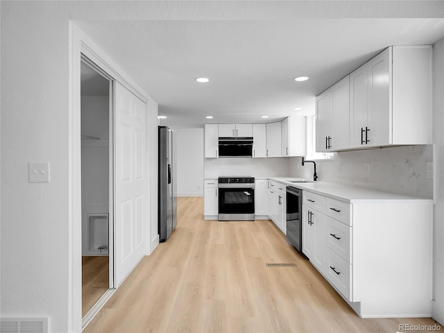 8694 E Eastman Ave, Denver, CO 80231 - kitchen featuring stainless steel appliances, range hood, light wood finished floors, white cabinets, and light countertops