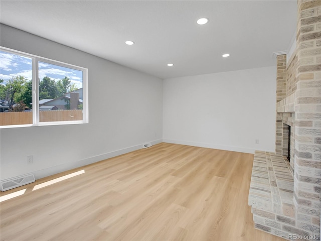 8694 E Eastman Ave, Denver, CO 80231 - unfurnished living room with a brick fireplace, recessed lighting, and light wood-style floors