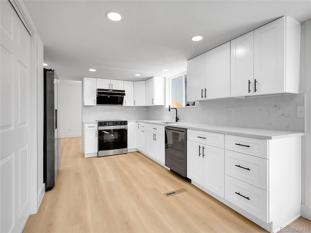 8694 E Eastman Ave, Denver, CO 80231 - kitchen featuring stainless steel appliances, exhaust hood, light wood-style floors, light countertops, and tasteful backsplash