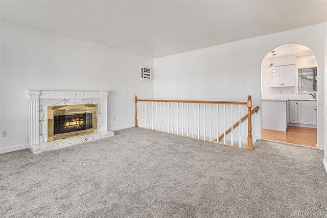 unfurnished living room with a tile fireplace, light wood-type flooring, and sink