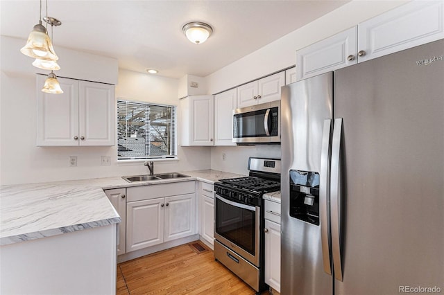 kitchen featuring white cabinetry, appliances with stainless steel finishes, decorative light fixtures, and sink